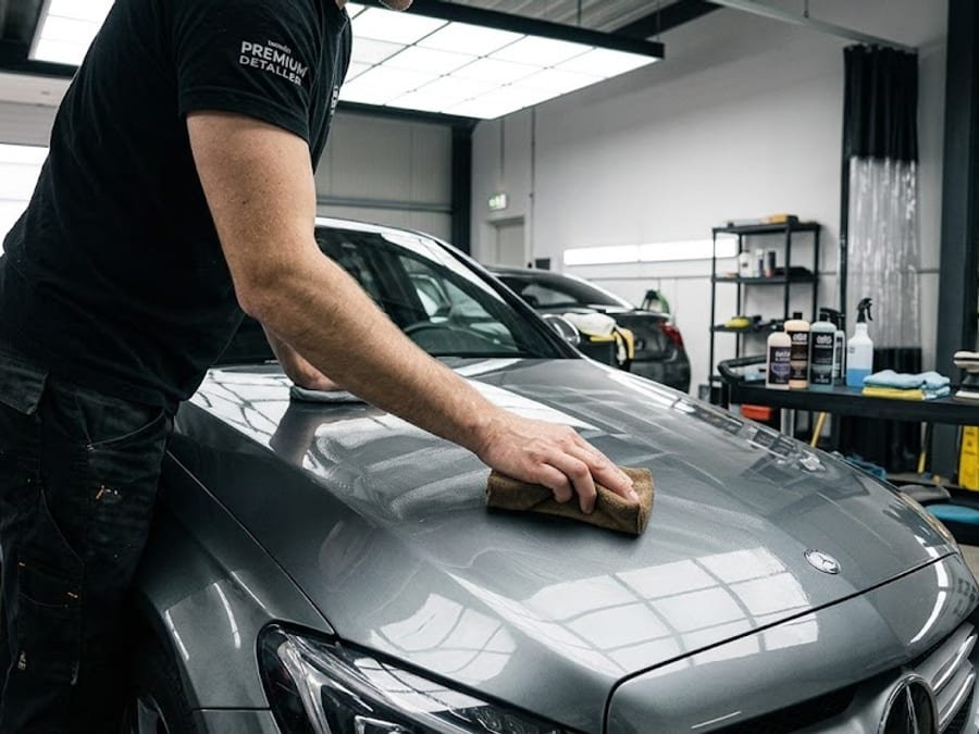 Detailer wiping the hood of a gray Mercedes